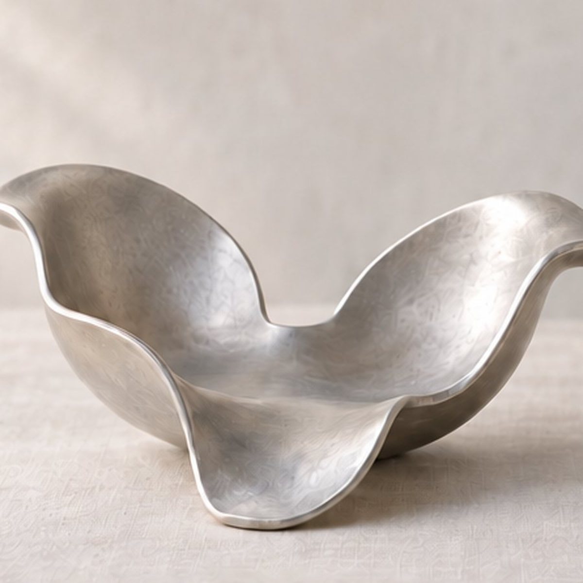Three-Rind Fruit Cradle — sand-cast aluminium fruit bowl shaped like peeled rind, natural silver finish, concept render
